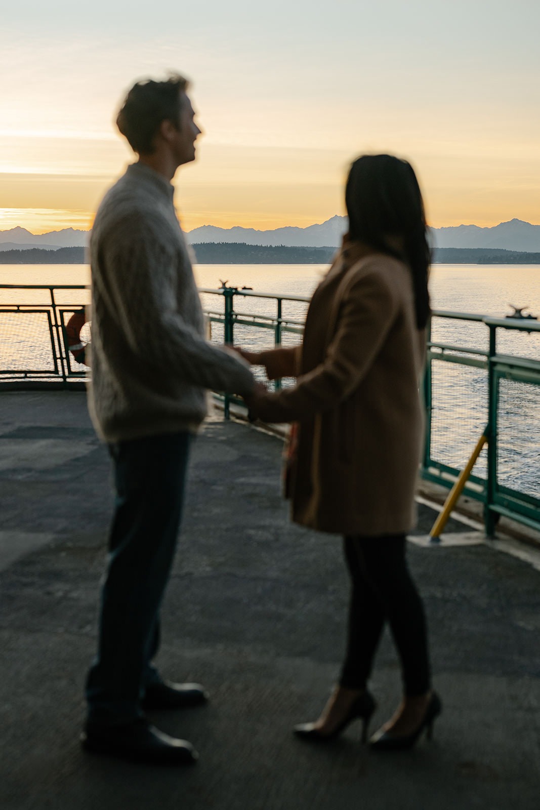 Soft blurred photo of a couple holding hands on the ferry deck at sunset
