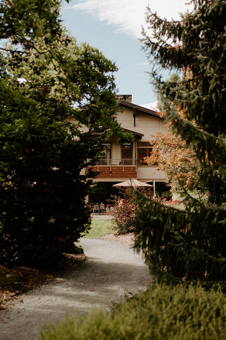 Garden pathway leading through mature trees toward the Willows Lodge venue buildings in Woodinville