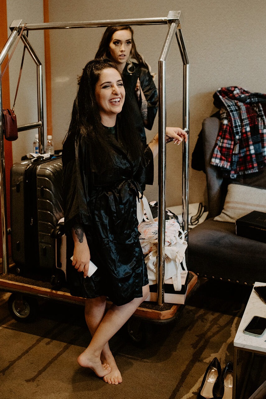 Two women laughing together in silk robes during bridal getting-ready preparations at Willows Lodge