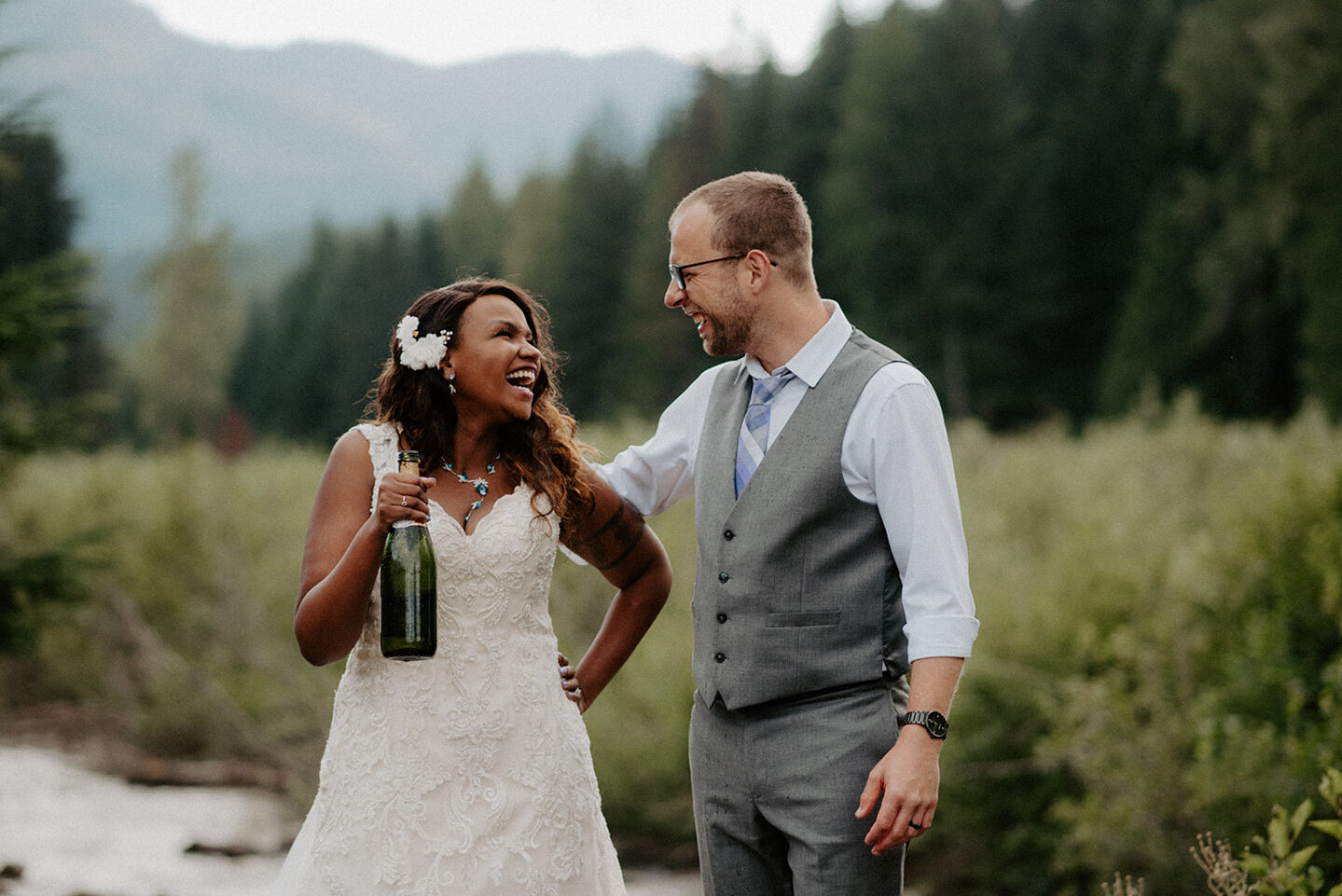 Bride and groom laughing together after popping champagne at their intimate Gold Creek Pond elopement