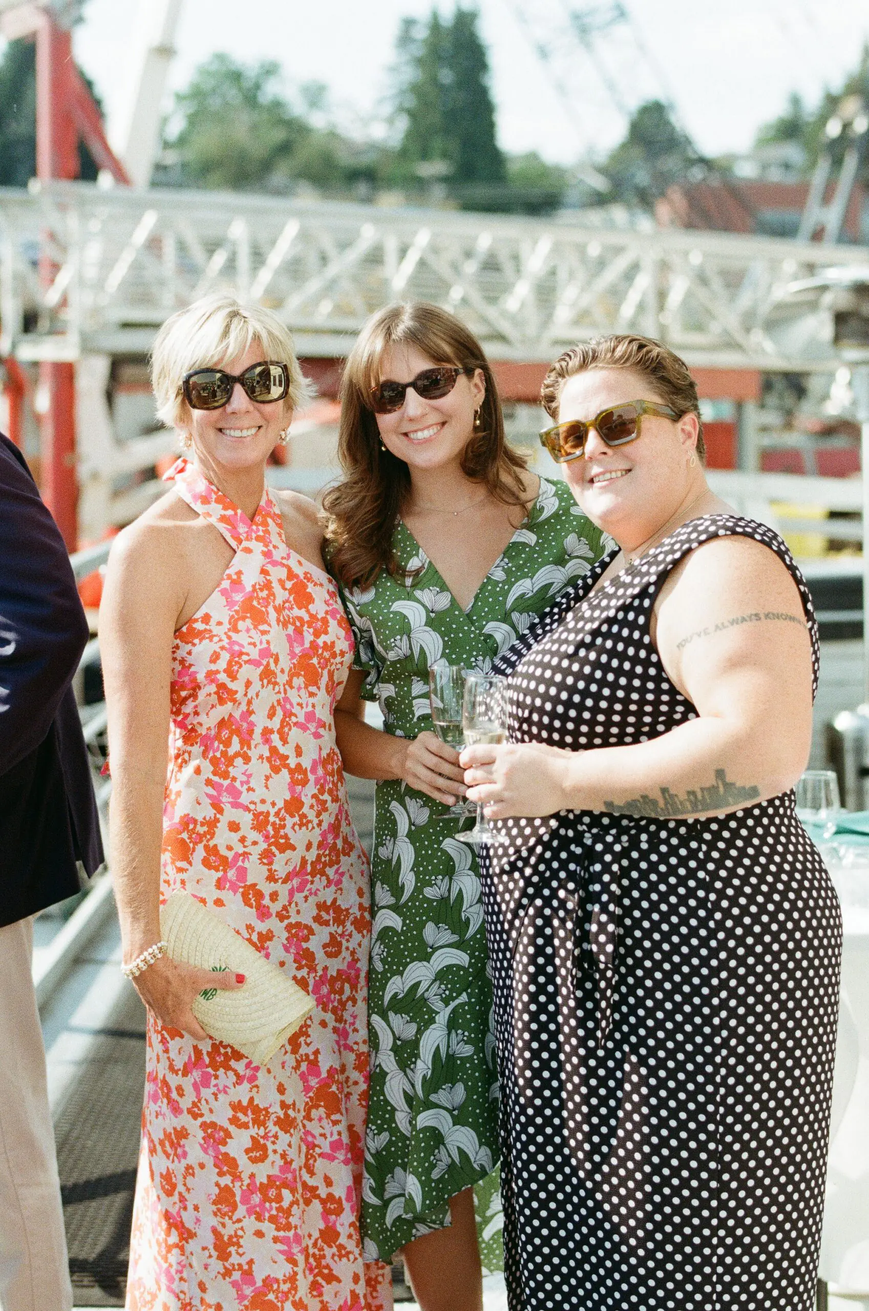 Three wedding guests smiling and holding champagne on the deck of MV Skansonia during cocktail hour