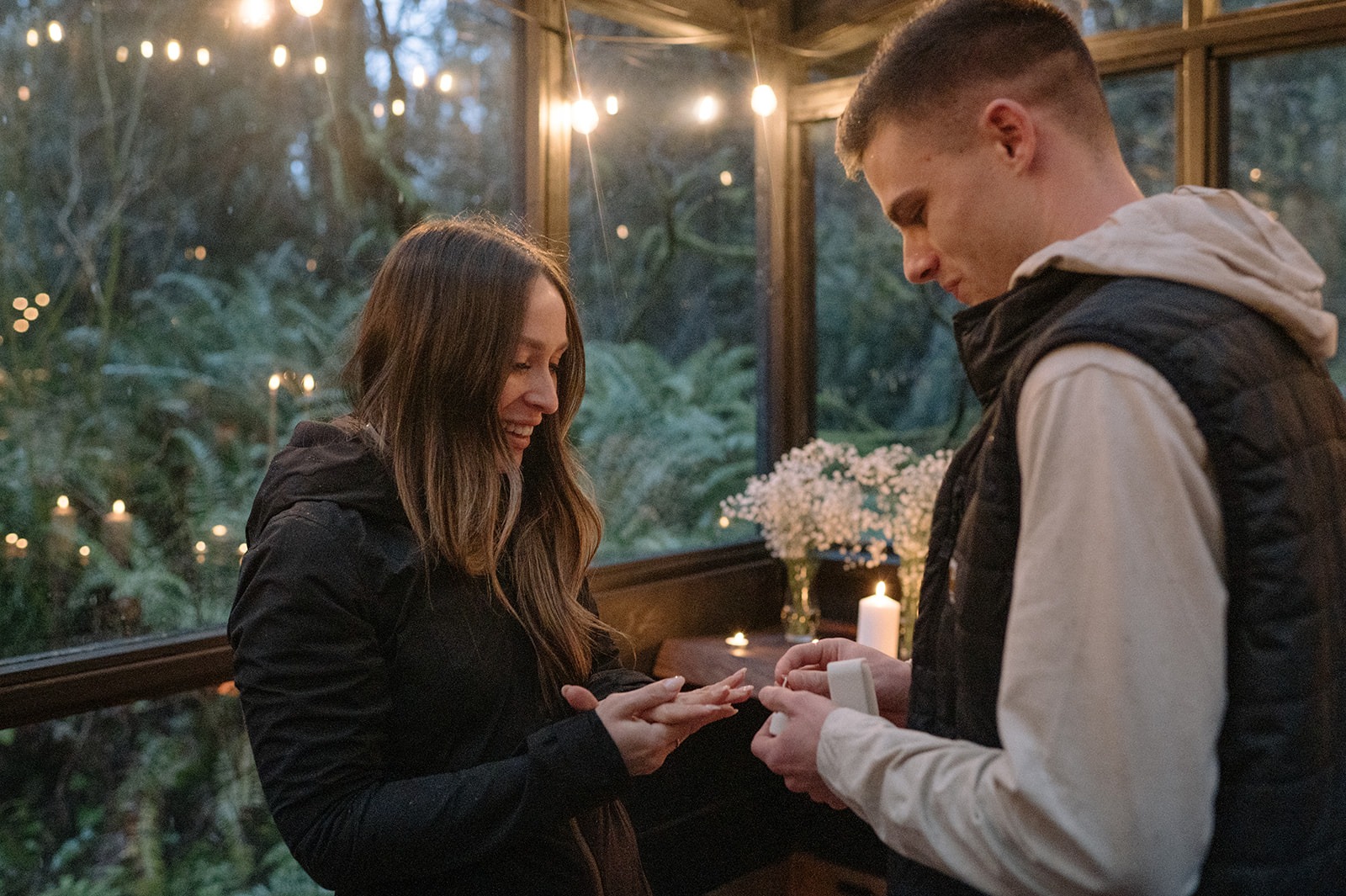 Bride-to-be admires her new engagement ring inside the candlelit sunroom at Canyon Creek Cabins in Granite Falls, WA
