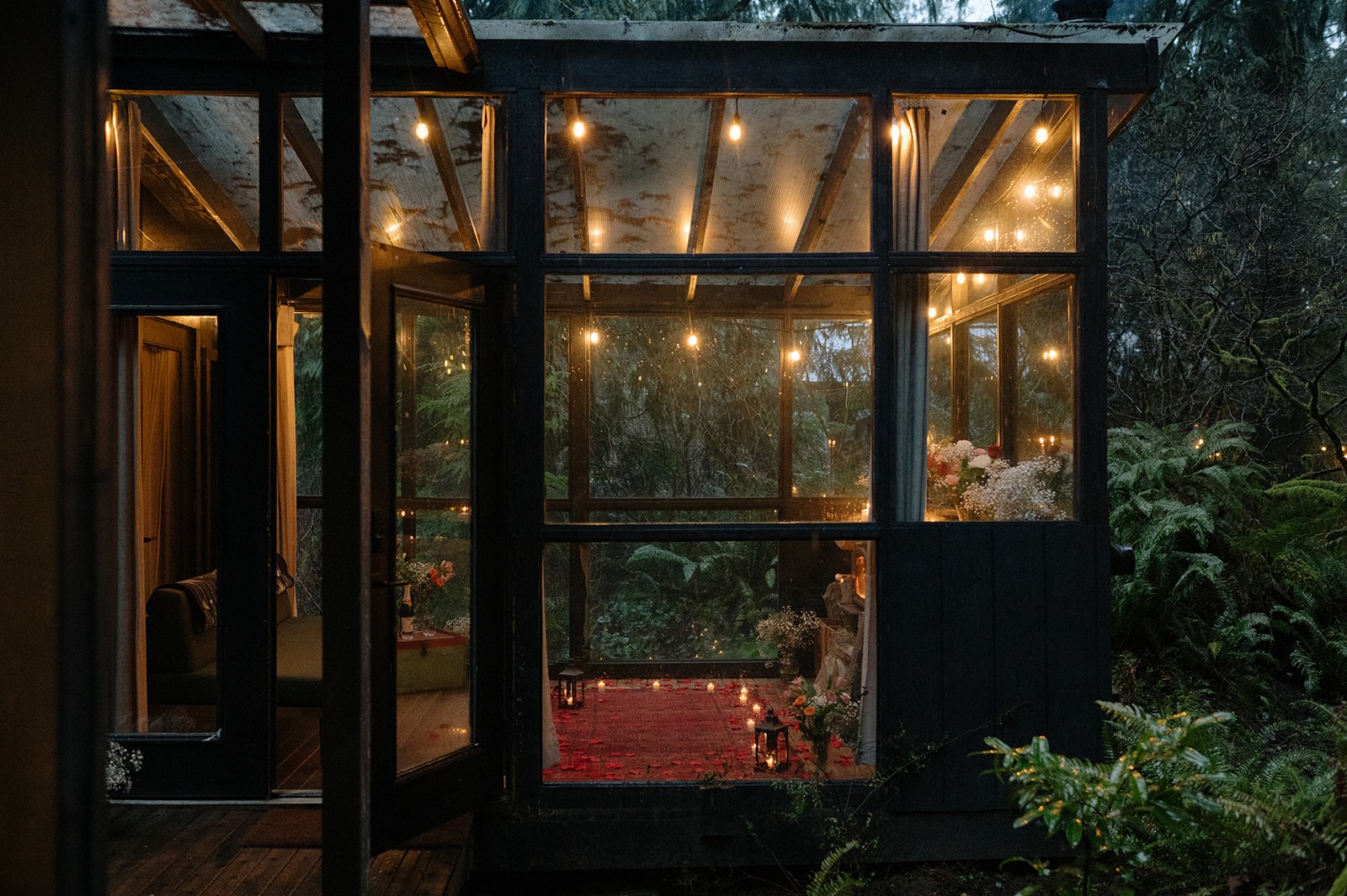 View through the open glass doors of the candlelit sunroom setup at Canyon Creek Cabins during a rainy Granite Falls proposal
