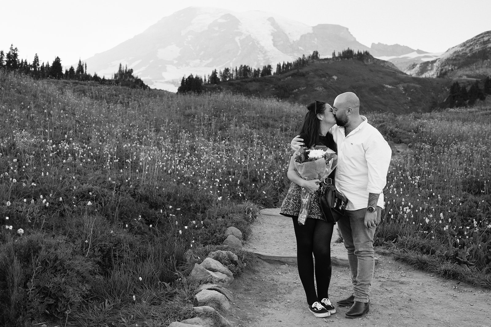 Bride-to-be holds her surprise bouquet as her fiancé kisses her cheek at Paradise after a surprise Mount Rainier proposal
