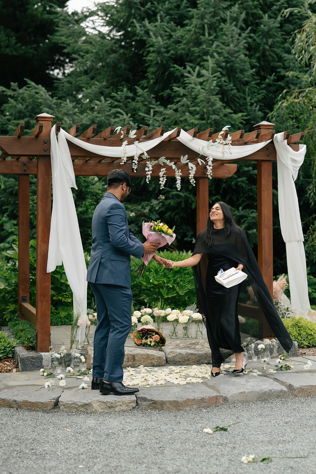 Priyanka laughs in surprise as Piyush hands her a bouquet at the floral arch during their Willows Lodge proposal