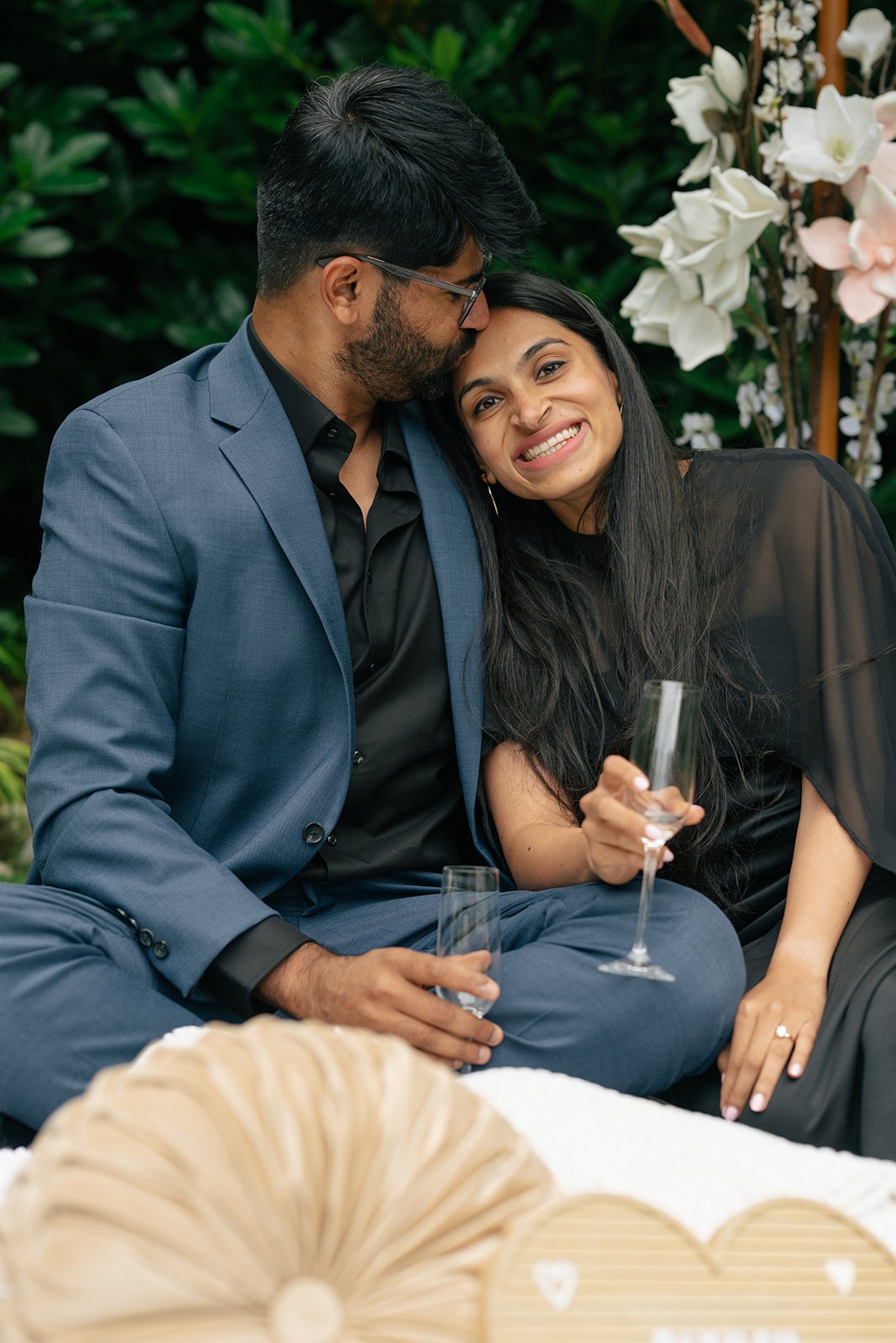 Piyush kisses Priyanka on the forehead as she smiles with a champagne flute during their post-proposal celebration at Willows Lodge
