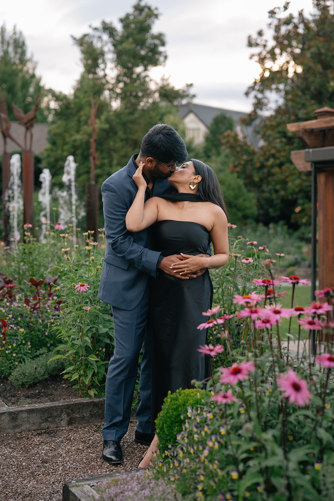 Woodinville engagement portrait of Piyush kissing Priyanka near the garden fountain at Willows Lodge