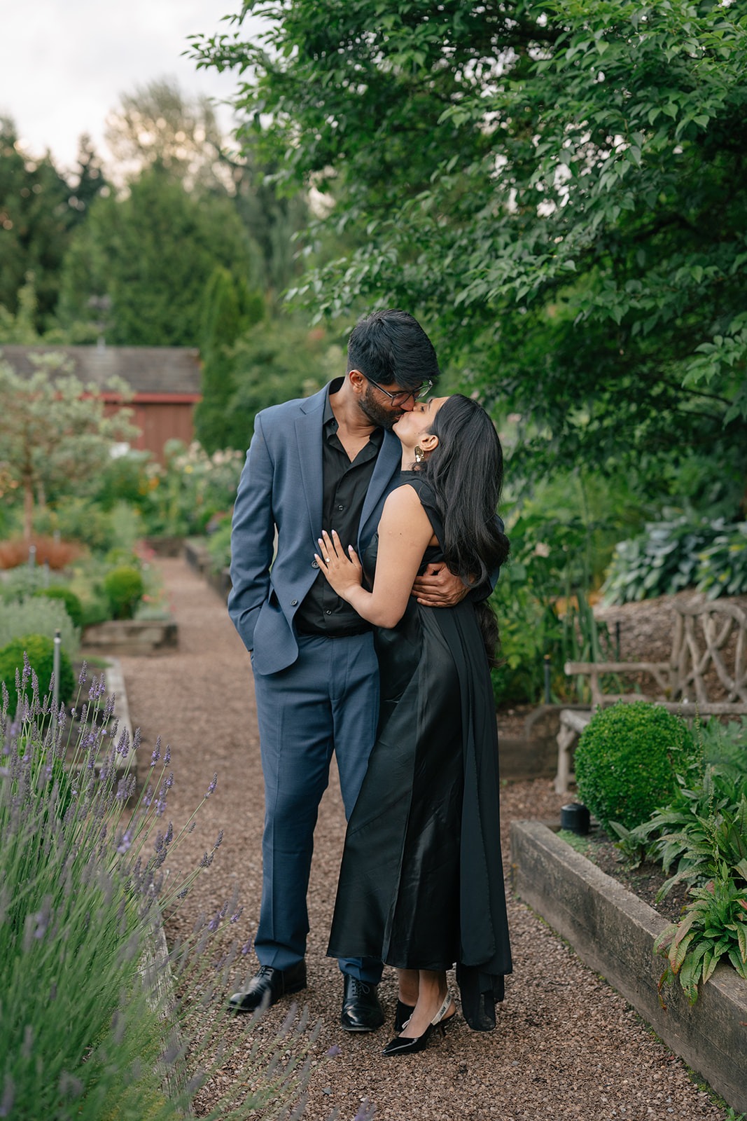 Newly engaged couple shares a kiss on the lavender-lined path at Willows Lodge in Woodinville