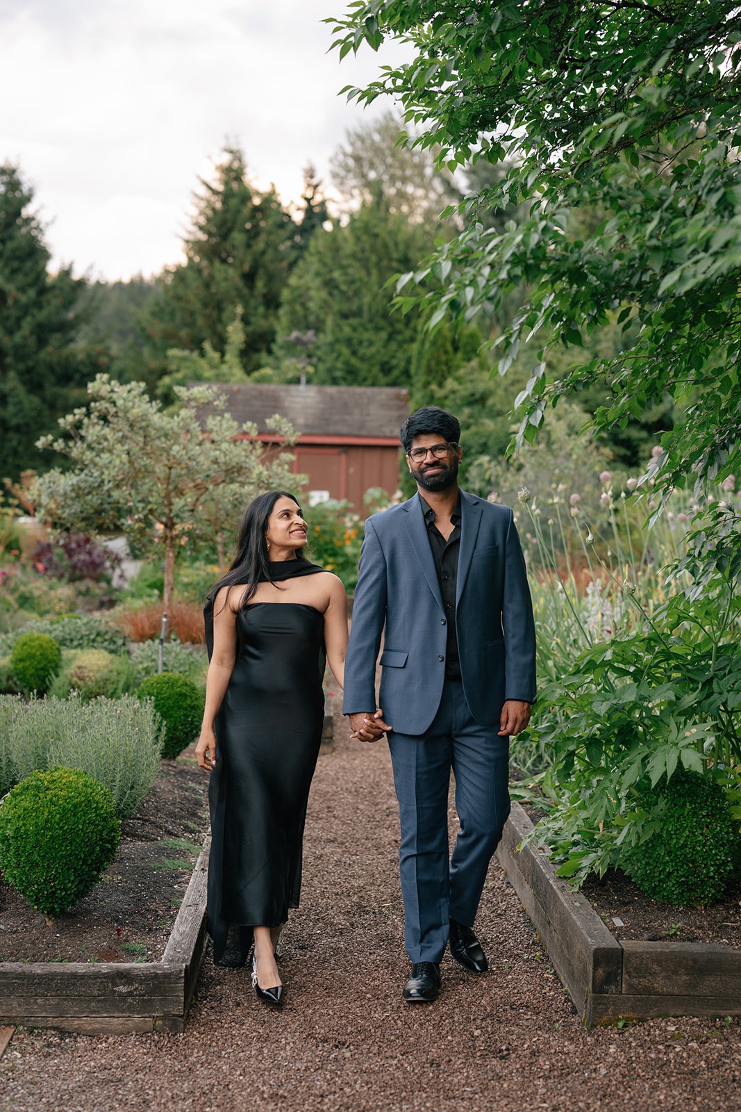 Newly engaged couple walks the garden path at Willows Lodge during their golden hour engagement portraits