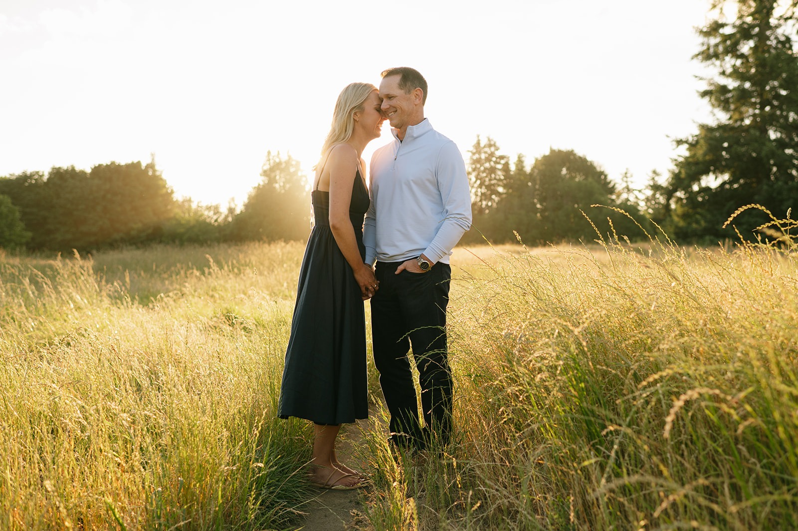 Couple shares a close kiss in the golden field engagement session light