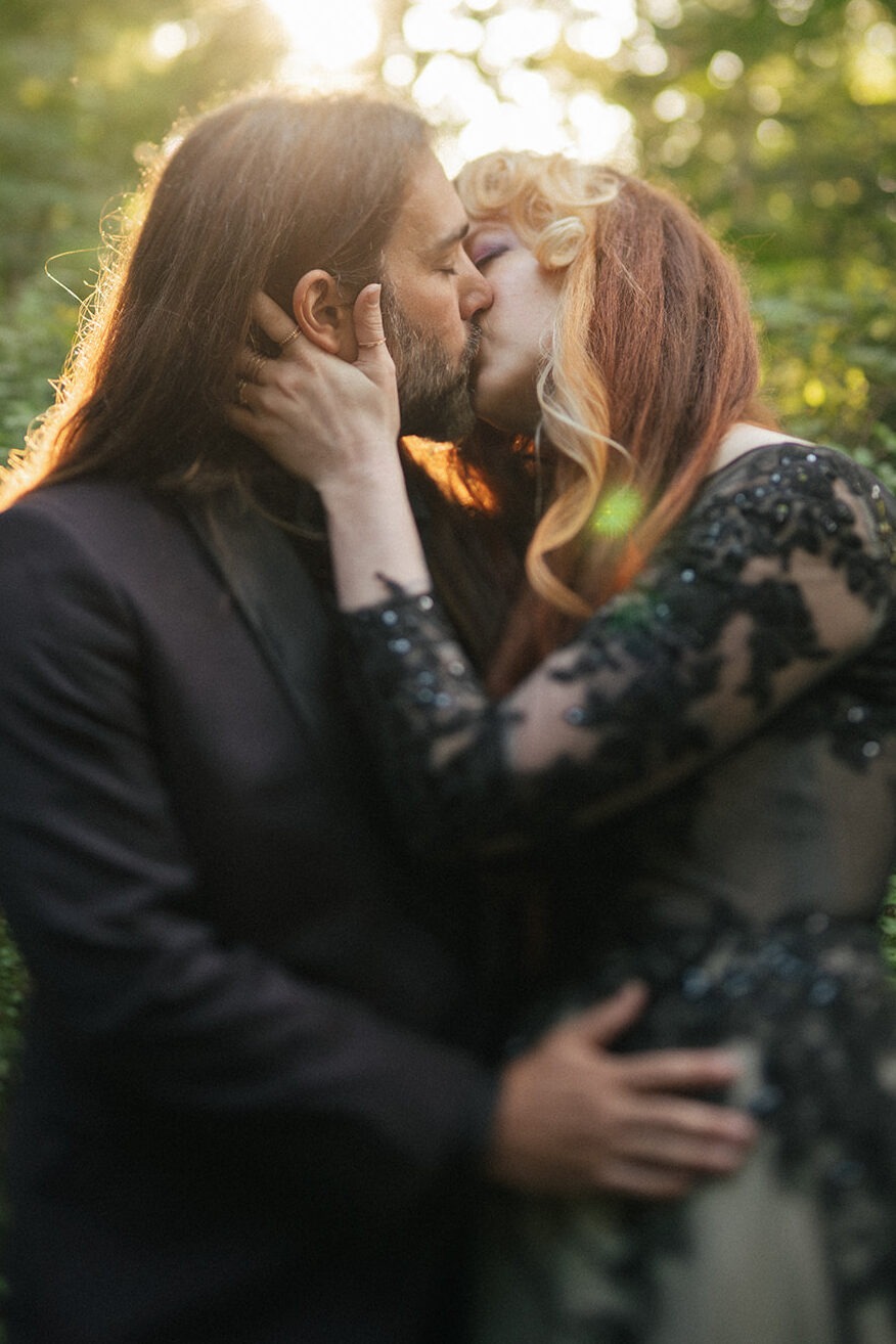 Close-up of the couple kissing, black lace sleeve visible against the groom's jacket