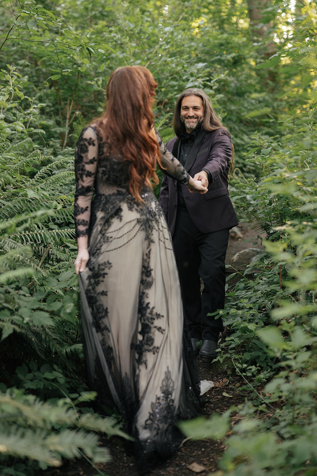 Couple walks hand in hand down a gravel path deeper into the woods