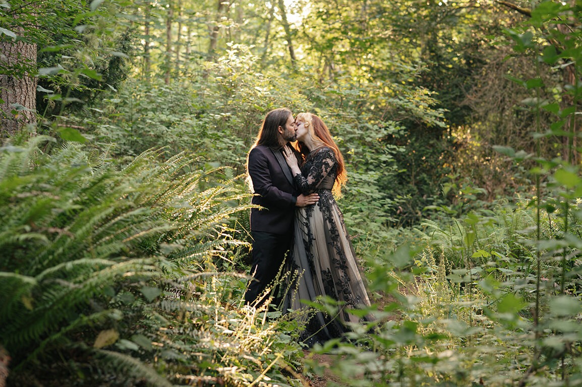 Couple kisses in a sunlit forest clearing