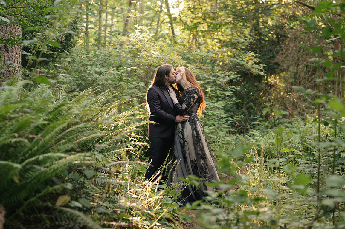 Couple kisses in a sunlit forest clearing