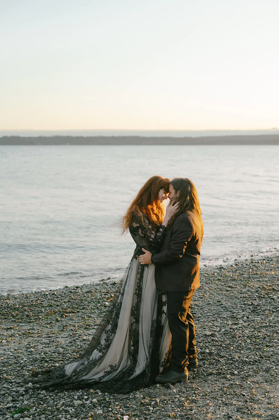 Couple kisses on the beach in this moody forest wedding portraits gallery, dress train trailing behind her