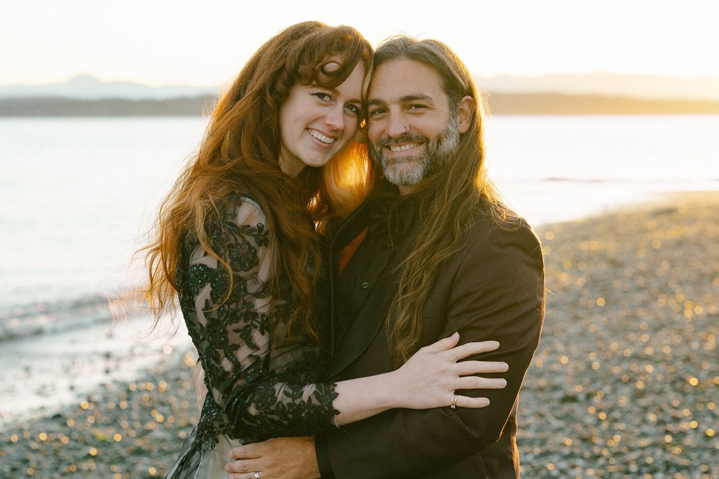Close portrait of the couple smiling at the camera in golden beach light