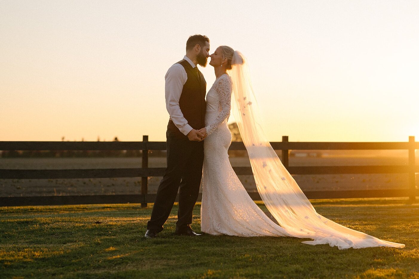 A cathedral veil catches the breeze during this romantic golden hour moment at a Saltbox Barn wedding. Reach out to capture your own romance.